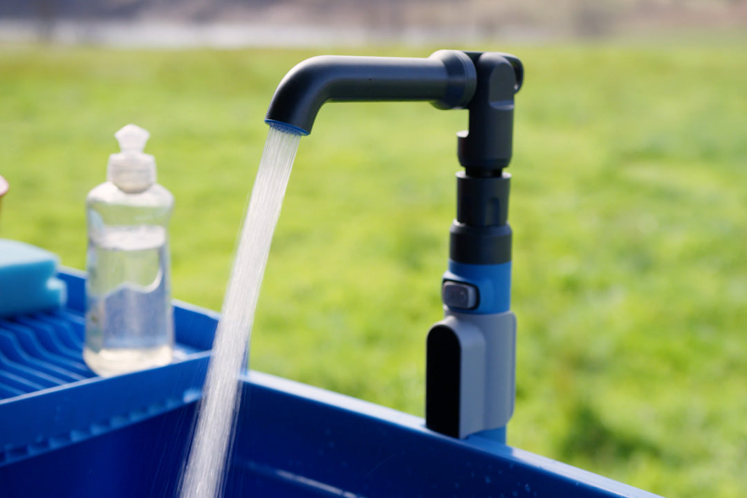 Water running from the Nomad faucet into the blue Nomad Sink, next to a bottle of dish soap