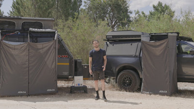 Hand attaching the Joolca Ensuite Mounted shower tent to the side of a 4WD.