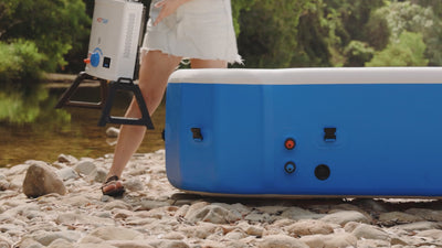 Hose being connected to the Joolca Hottub inflatable spa beside a rocky river.