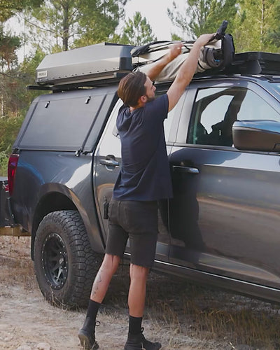 Man in a cap setting up the Joolca Ensuite Mounted Single tent in seconds.