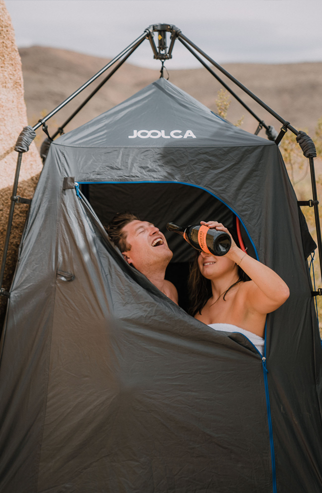 Two people inside a Joolca tent in a desert setting